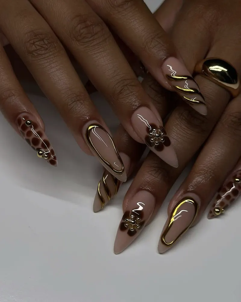 Nude and gold nail art photographed close, one hand resting over the other