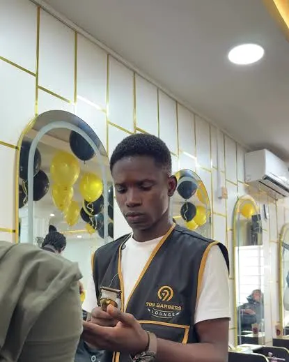 A 709 barber in the lounge vest trimming a client's hair between the arch mirrors