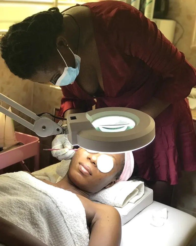 A facial in progress under the treatment lamp, technician working above the client